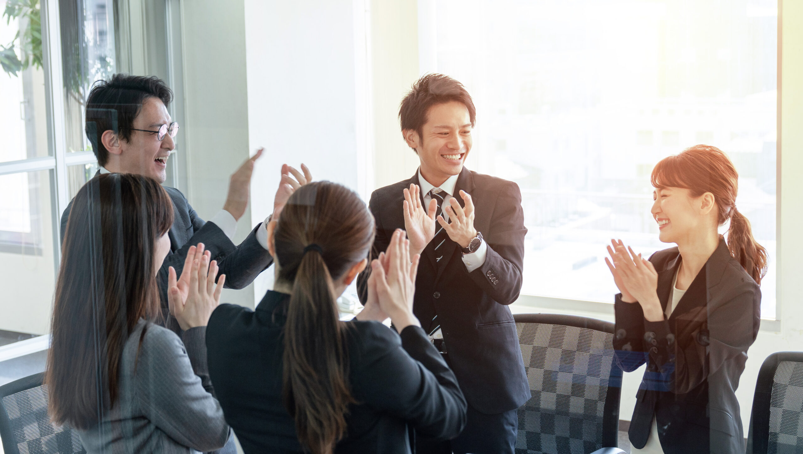 拍手し合う若い社員｜企画｜イベント｜コミュニケーション