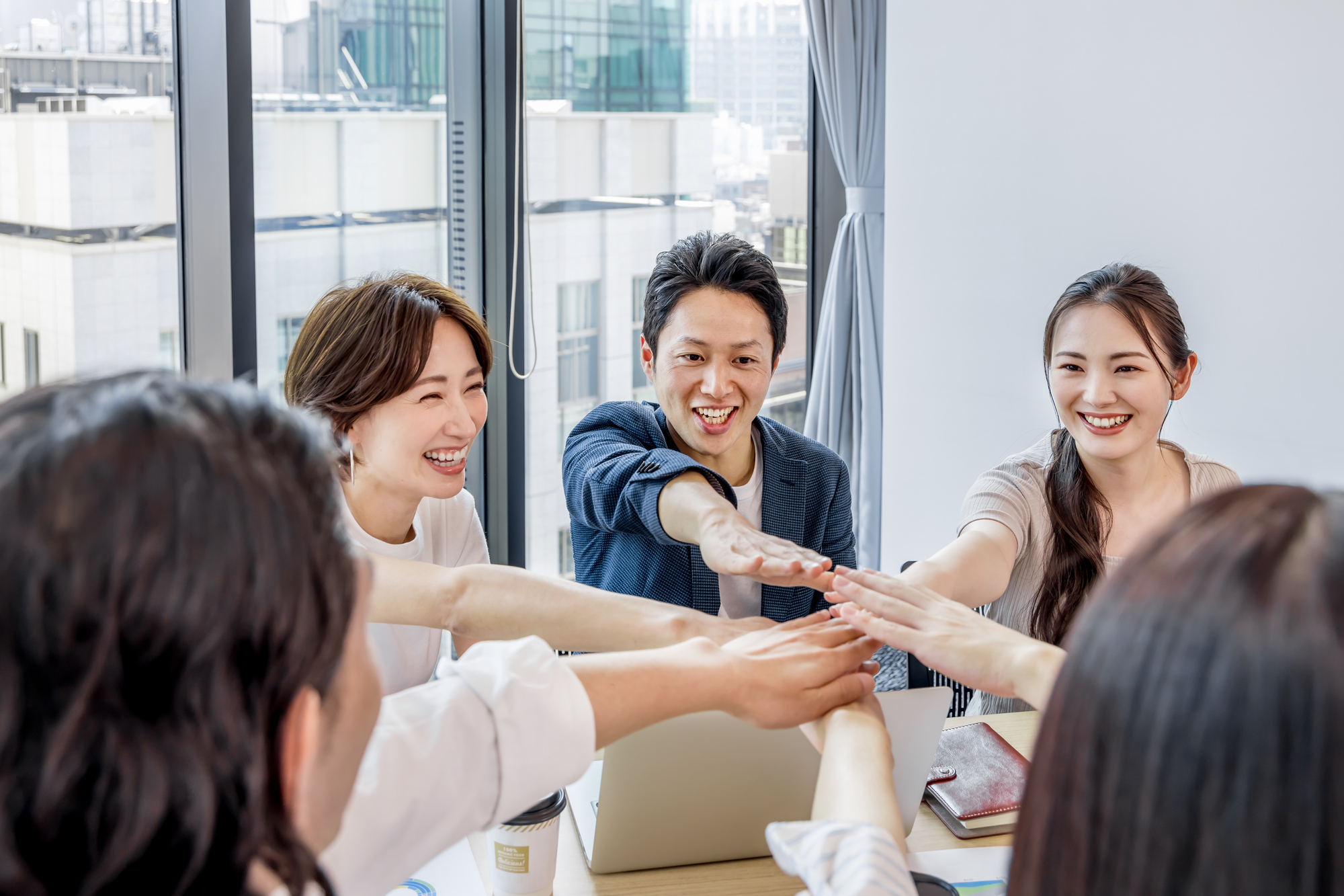 オフィスで手を合わせる男女｜コミュニケーション｜社内